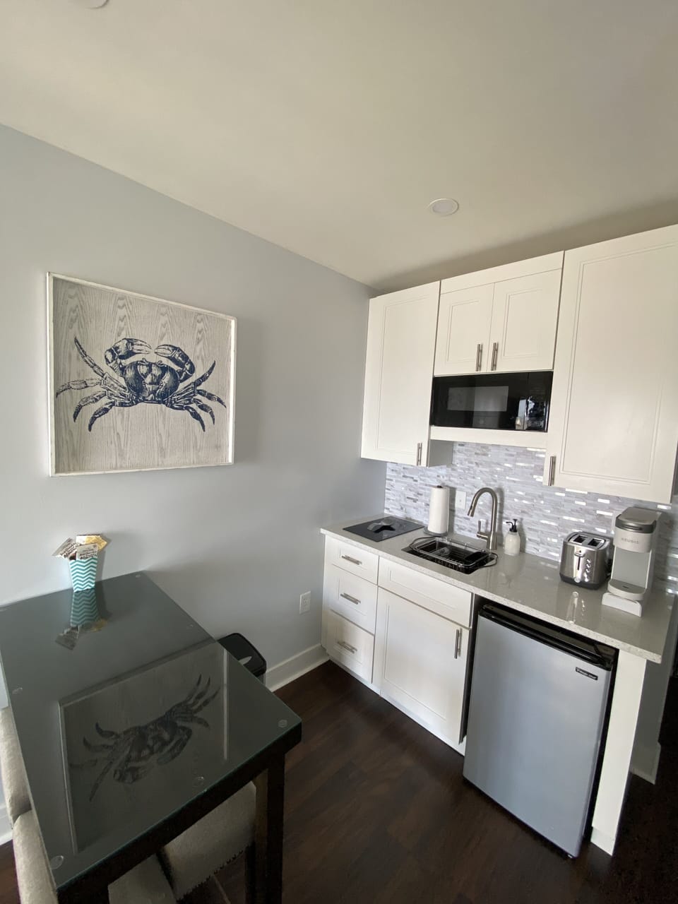 Kitchenette with table for four,  microwave, toaster, cooktop and mini fridge.