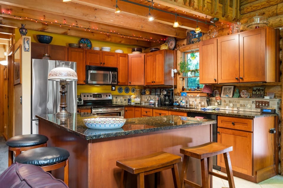 Cook w/ ease in the warm kitchen featuring granite counters, wood cabinetry & bar seating.