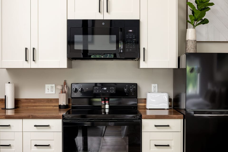 Modern kitchen w/ full-size stove, microwave & sleek cabinetry for easy cooking.