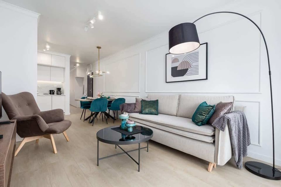 A connected living and dining area with a stylish chandelier, teal chairs, and a spacious layout that blends comfort with sophistication.

