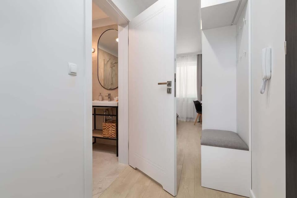 A hallway with sleek white doors leading to different rooms, featuring minimalist decor and a bright, clean design.

