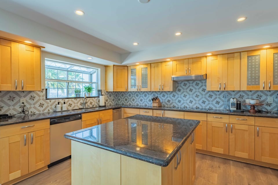 This spacious gourmet kitchen welcomes you with warm wood cabinetry, granite countertops, and elegant patterned tile backsplash—perfect for preparing memorable meals during your stay.