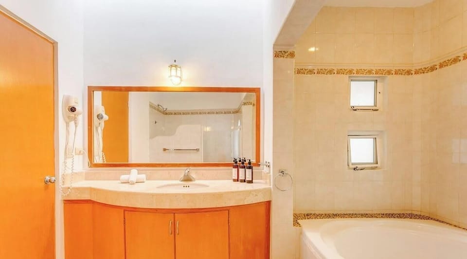 Bright bathroom featuring a large mirror and a spacious bathtub with pebble tile accents.