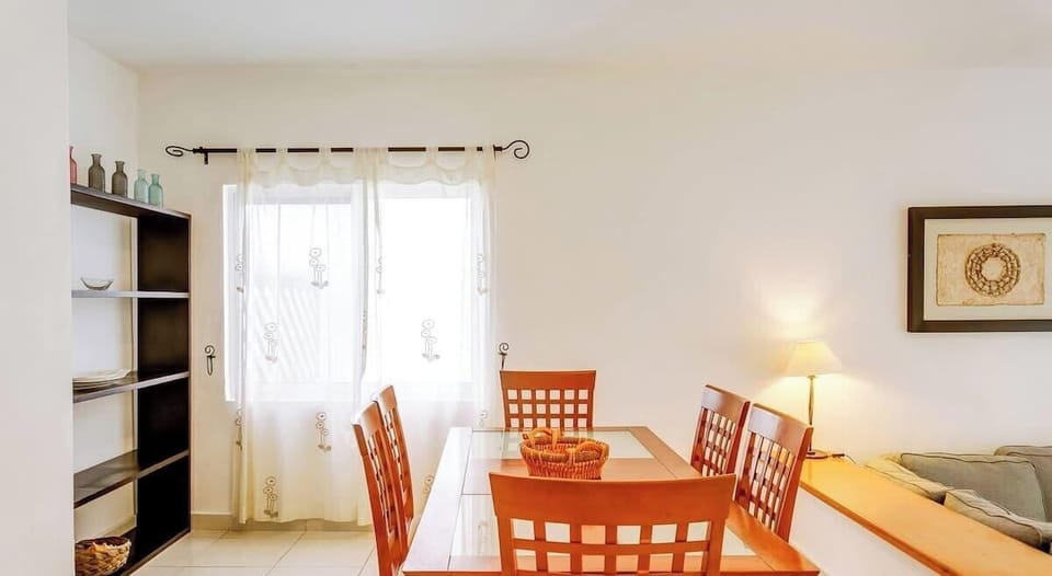 Dining area with wooden table and natural light from sheer curtains