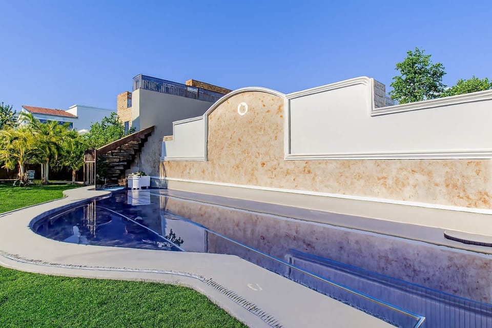 Modern outdoor pool area with a curved design and surrounding green lawn