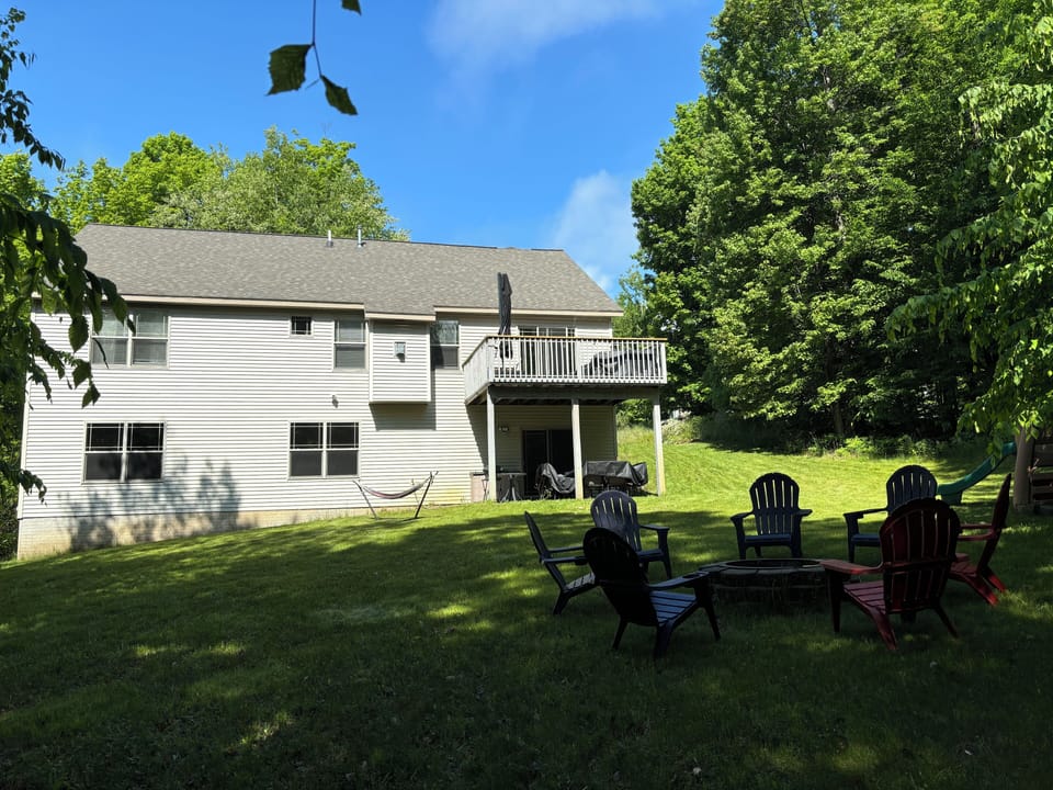 Backyard with outdoor firepit, chairs, seating area under the deck and gas grill