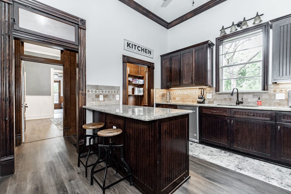 Kitchen with plenty of dishes, large fridge, an island, and pantry.