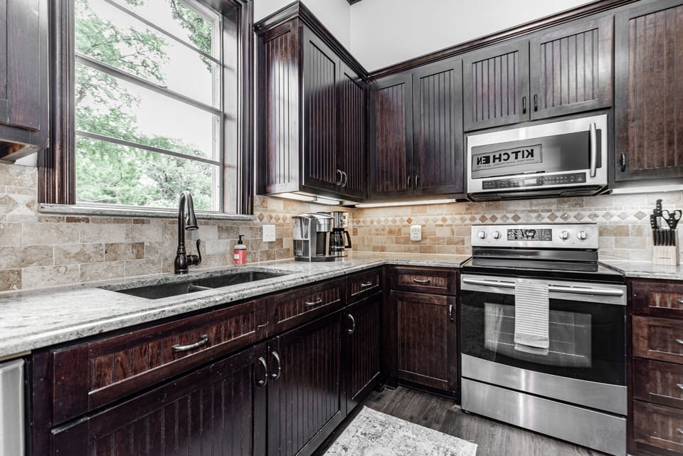 Kitchen with microwave, oven, stove top, and coffee maker.
