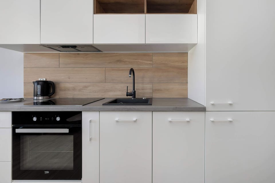 Kitchenette highlighting white cabinetry and a clean countertop. The wooden backsplash continues, adding warmth to the design. The layout looks functional and minimal.