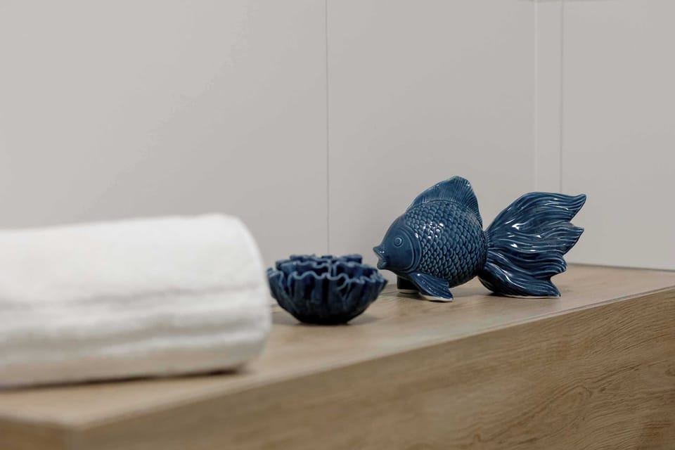 A close-up of neatly folded white towels placed on a wooden surface. A small decorative blue item sits beside them. The arrangement suggests attention to detail for guests.
