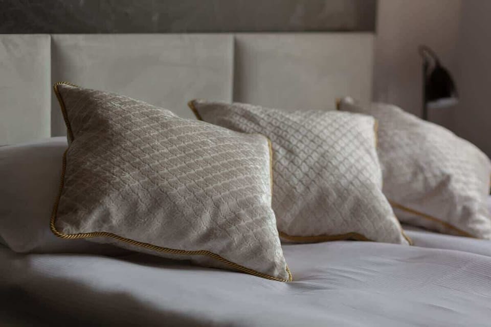 A bedroom close-up showcasing decorative white and beige pillows neatly arranged on a soft bed.