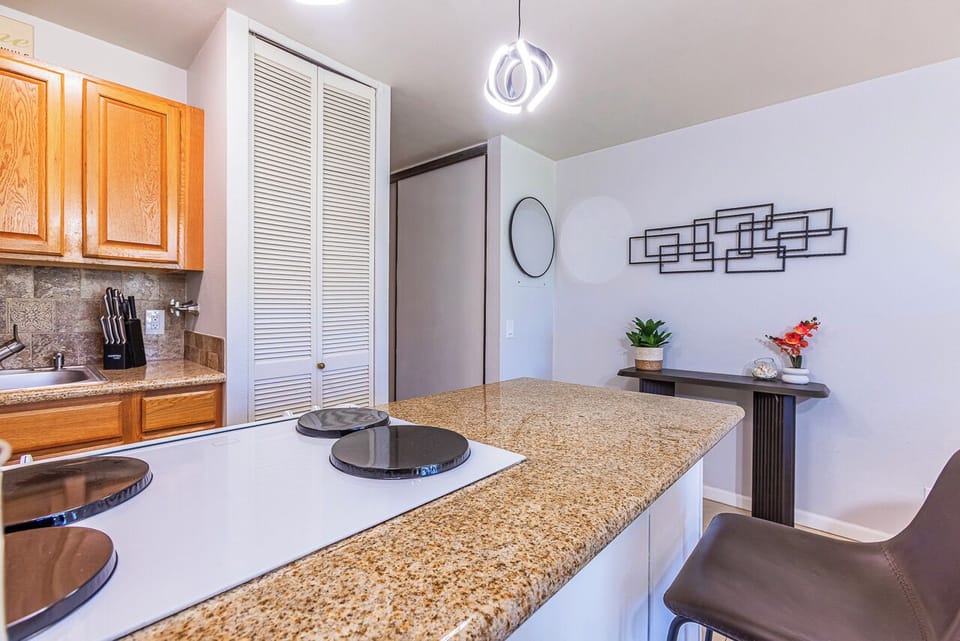 Gather around the spacious granite breakfast bar for morning coffee or casual meals. The modern pendant lighting adds a warm touch to your fully-equipped kitchen space.