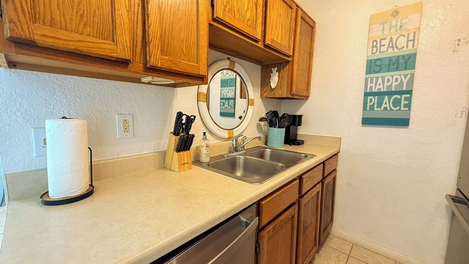 Your fully equipped kitchen awaits with everything you need to prepare meals, featuring warm wood cabinets and cheerful beach-themed decor.