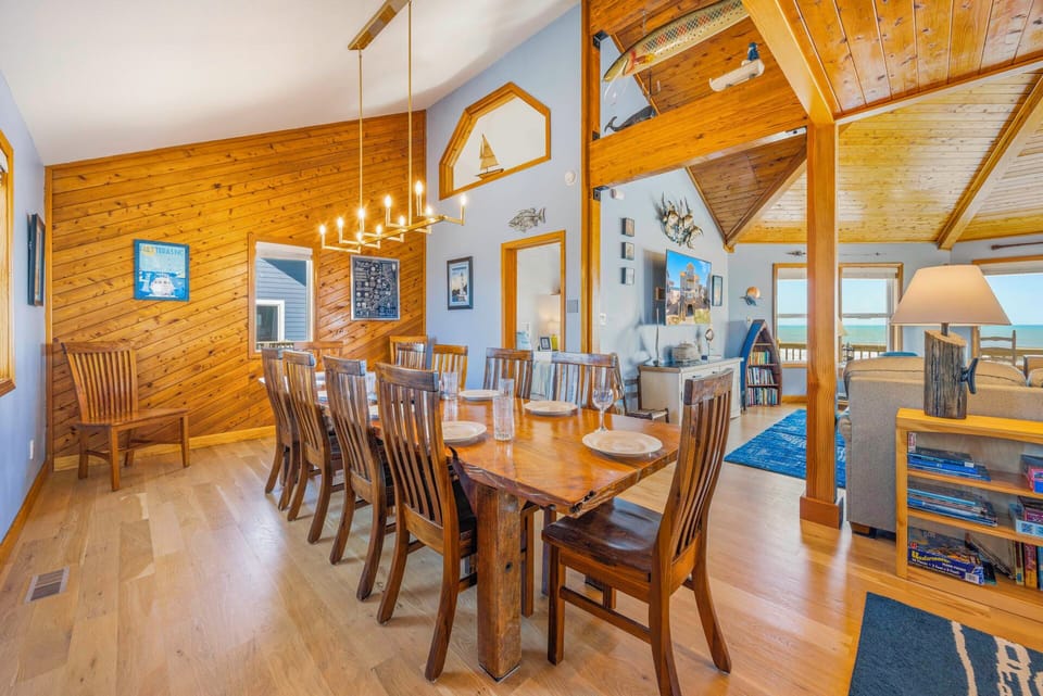Gather around this warm wooden dining table where conversations flow as freely as the ocean breeze through cathedral ceilings.