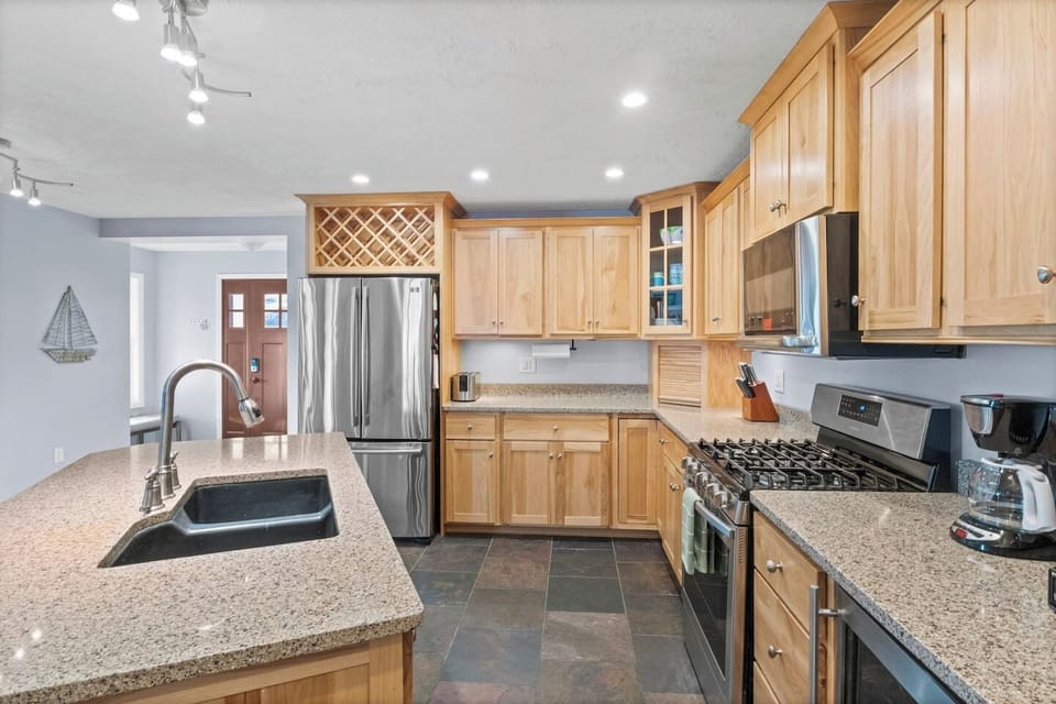 Fully equipped kitchen designed for culinary enthusiasts, featuring a central island with a sink for convenient meal preparation and all the necessary cooking essentials."
