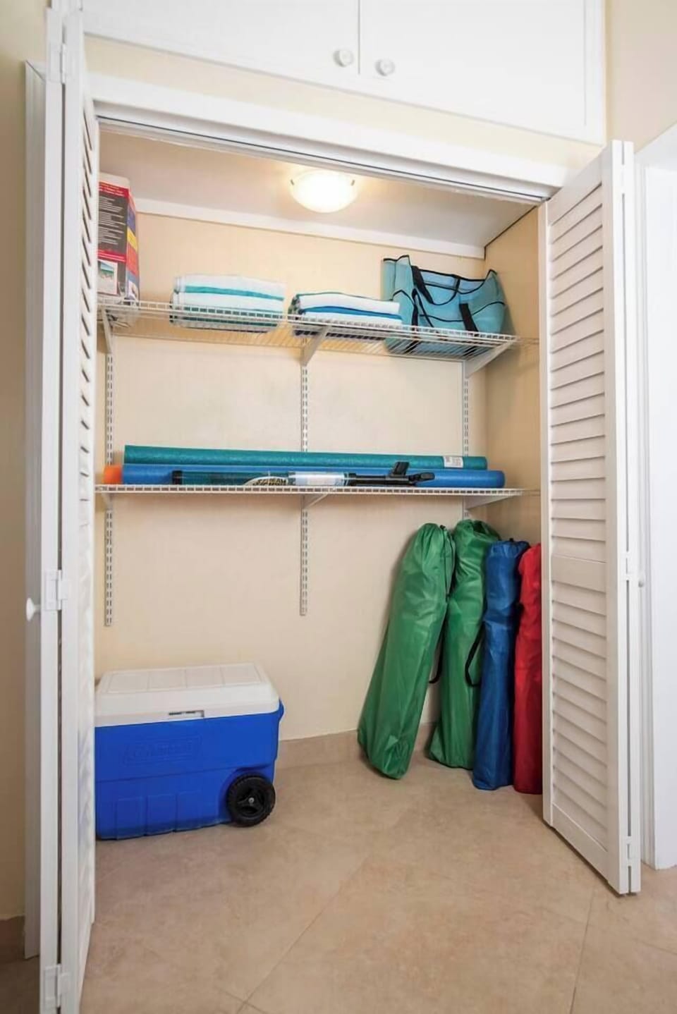Hallway closet with beach amenities. Included are noodles, stream blasters, beach chairs, beach towels and a cooler.