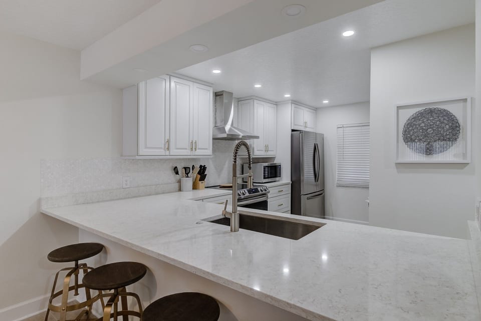 The kitchen area features ample storage cabinets and includes complete amenities such as a microwave oven, coffee maker, dinnerware, and cookware.
