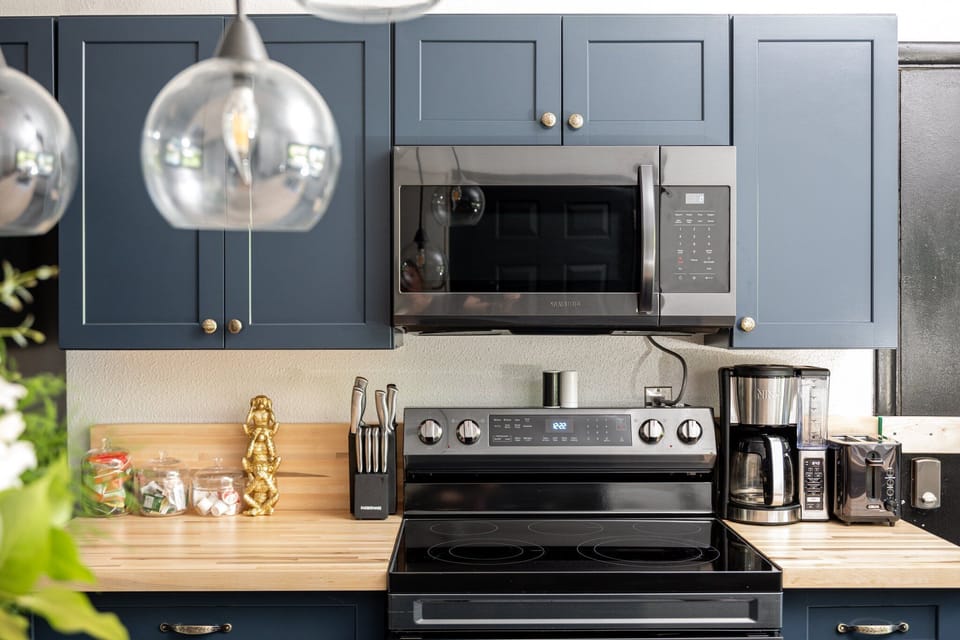 Sleek kitchen setup w/ stainless steel range, microwave & warm wood countertops.