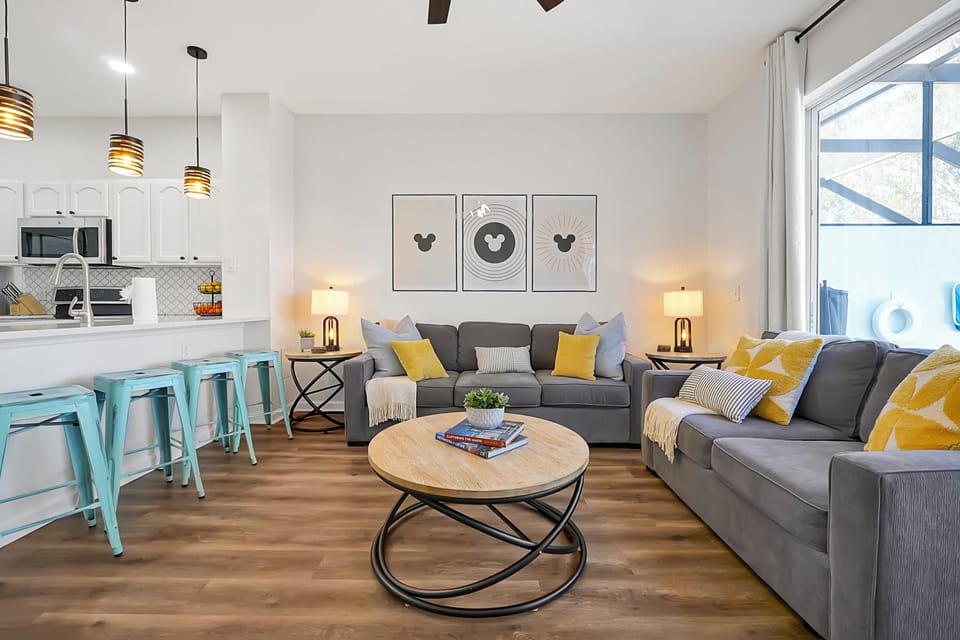 Your Disney home base: an airy, open-concept living room beside a family-ready kitchen. Settle into soft sofas spread out around the round coffee table, and fuel up at the island. Easy flow for board games, meal prep, and bedtime chats after a magical day.