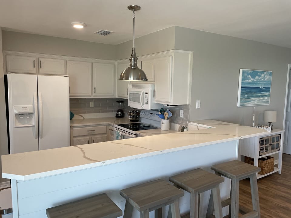 The rest of the kitchen with bar top and 4 stools 