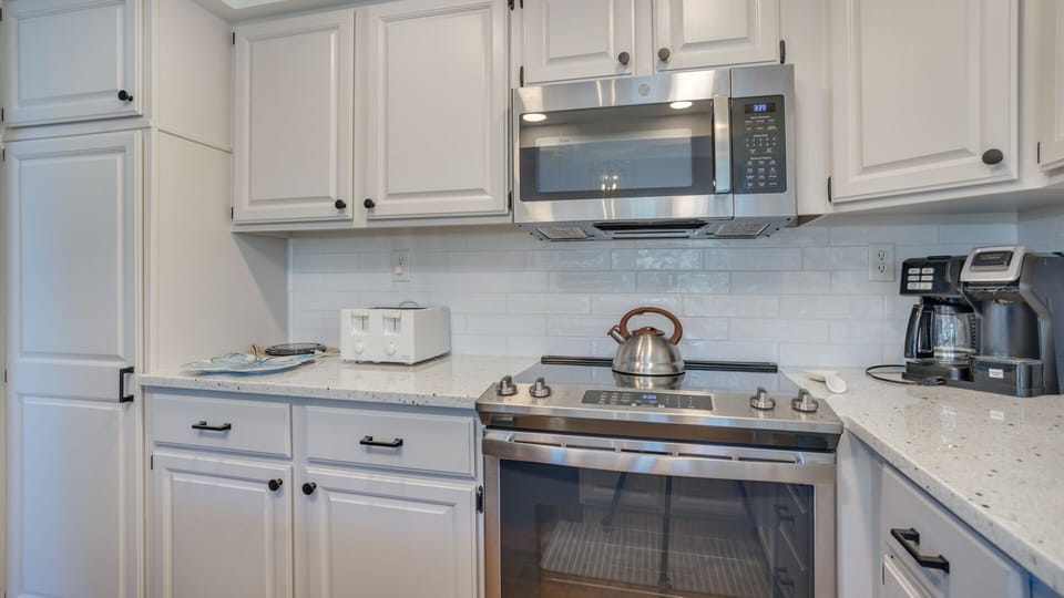 This well-appointed kitchen blends style and function with crisp white cabinetry, granite countertops, and stainless steel appliances.