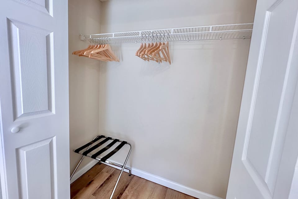 Spacious closet with hangers and luggage rack