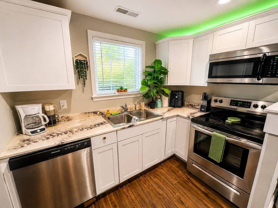 Modern kitchen with white cabinets, black appliances, microwave, and full fridge—fully stocked with pots/pans and ready for your stay.