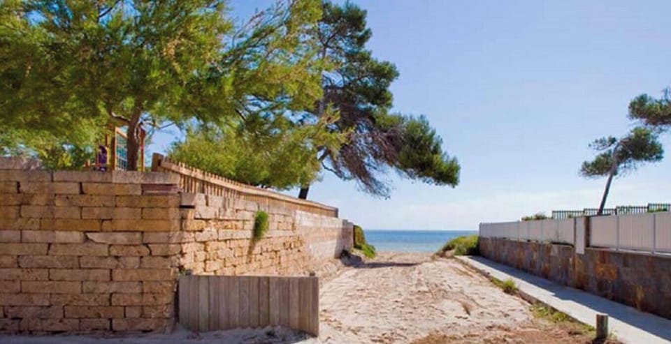 Pedestrian access to the beach near Villa Mediterranean, surrounded by pine trees and stone walls, offering easy access to the sea.