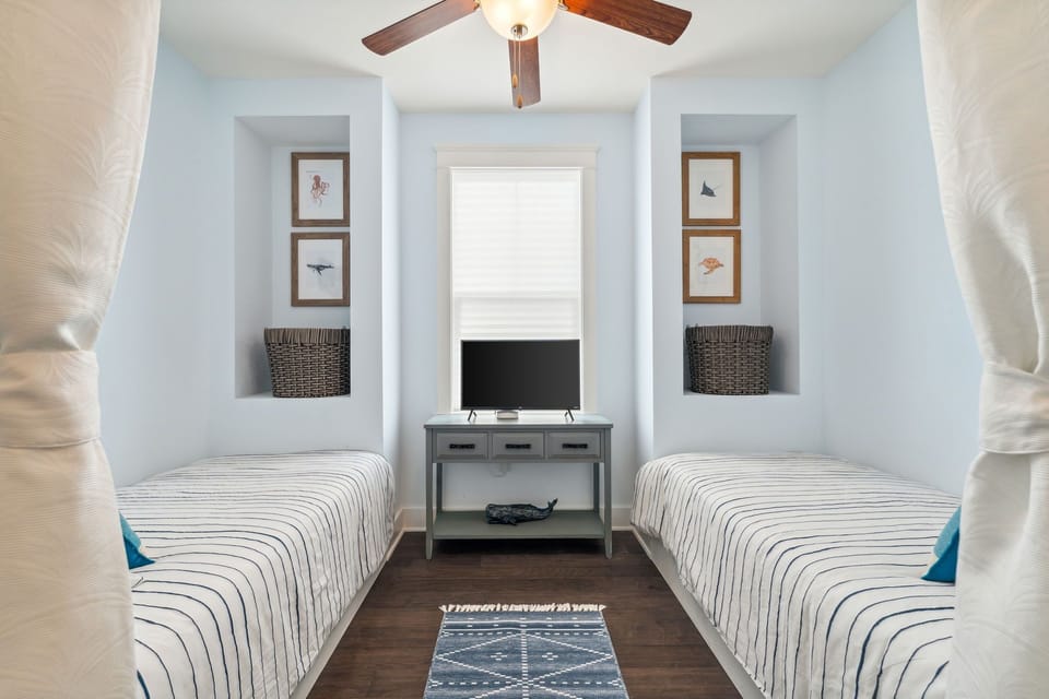 Upstairs bedroom 5 with two twin beds, smart TV and a black-out curtain divider.