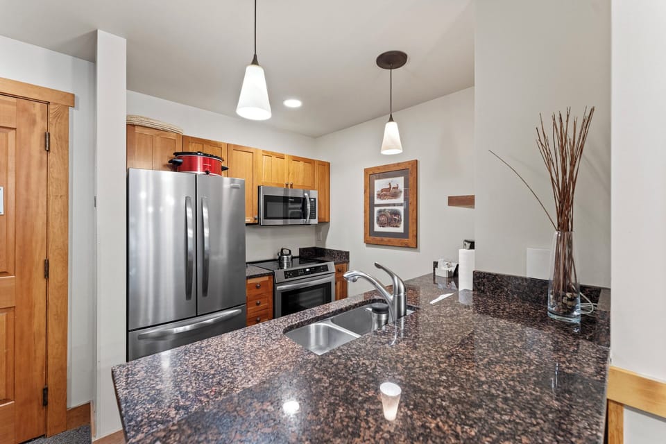Your fully-equipped kitchen awaits with granite counters, stainless appliances, and pendant lighting—perfect for preparing meals during your stay.