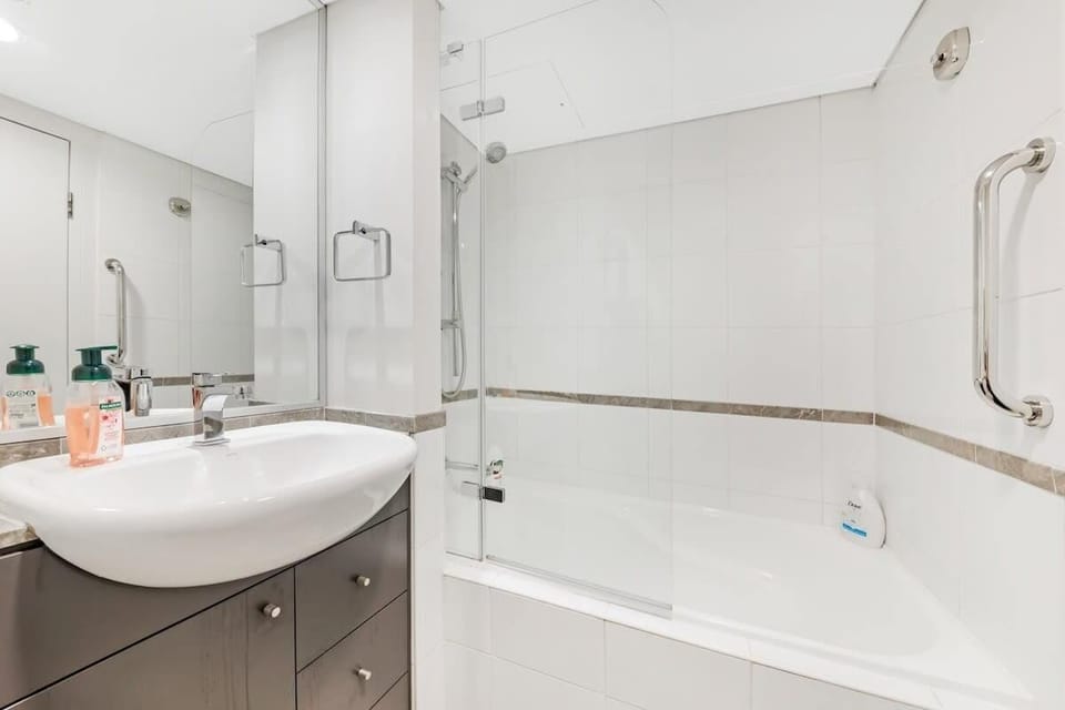 Bathroom with vanity, mirror, bathtub with shower, and toilet.