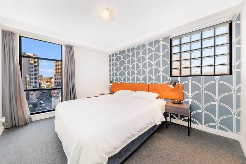 BedroomBedroom featuring a king-size bed, stylish feature wall, bedside tables, and city views.