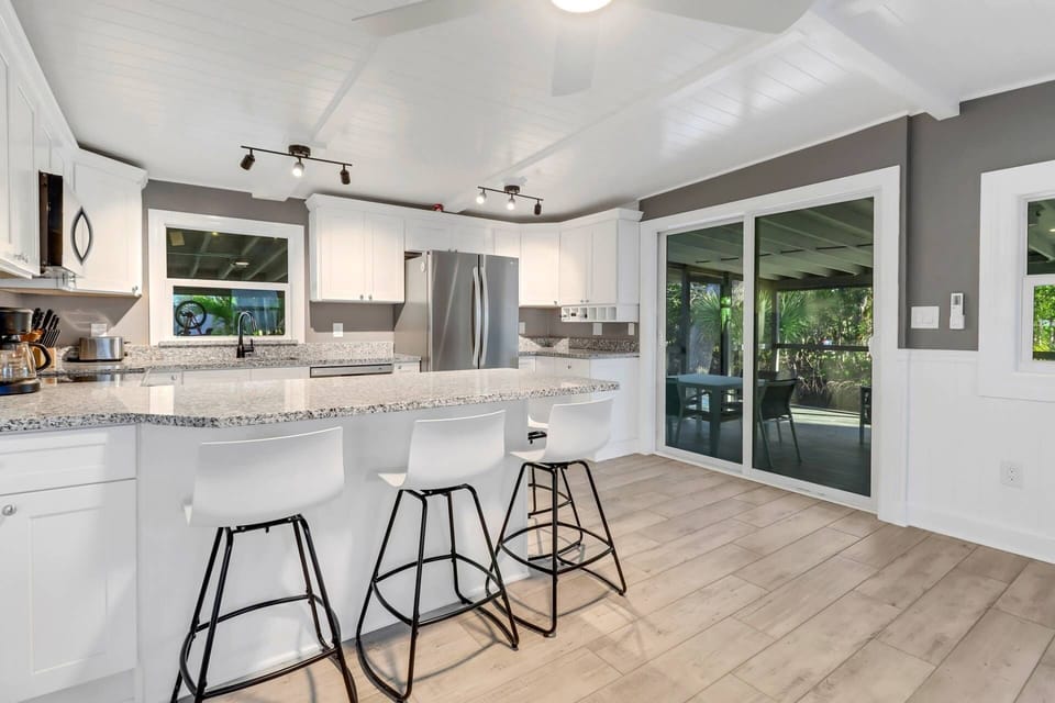 An eating bar with 4 bar stools is adjacent to the sliding doors that open to the outdoor dining on the fully screened lanai.