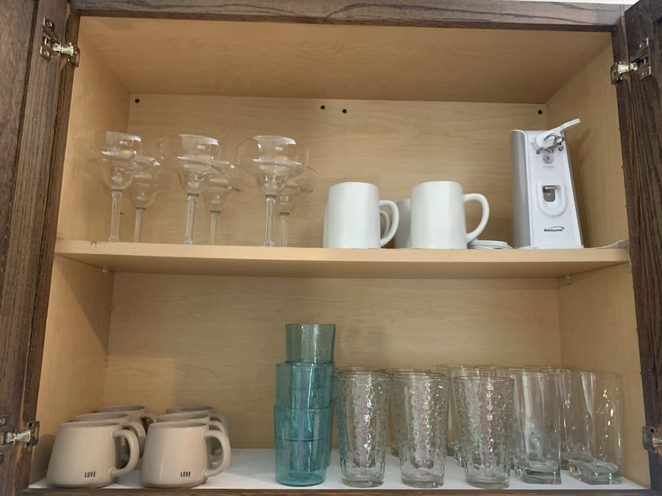 Fully stocked with glasses, dishes, and silverware. 