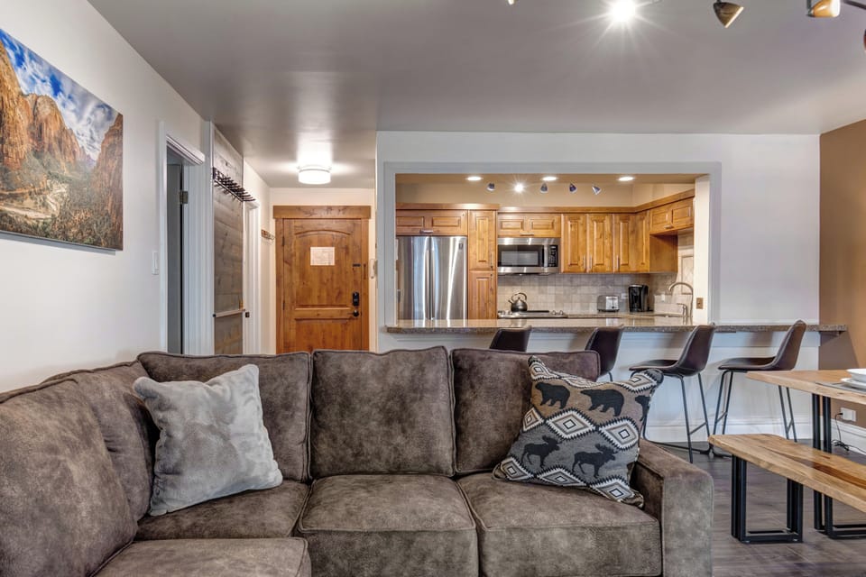 Settle into your inviting living space with plush seating and an open-concept kitchen featuring warm wood cabinetry and modern appliances - perfect for relaxing after a day of adventure.