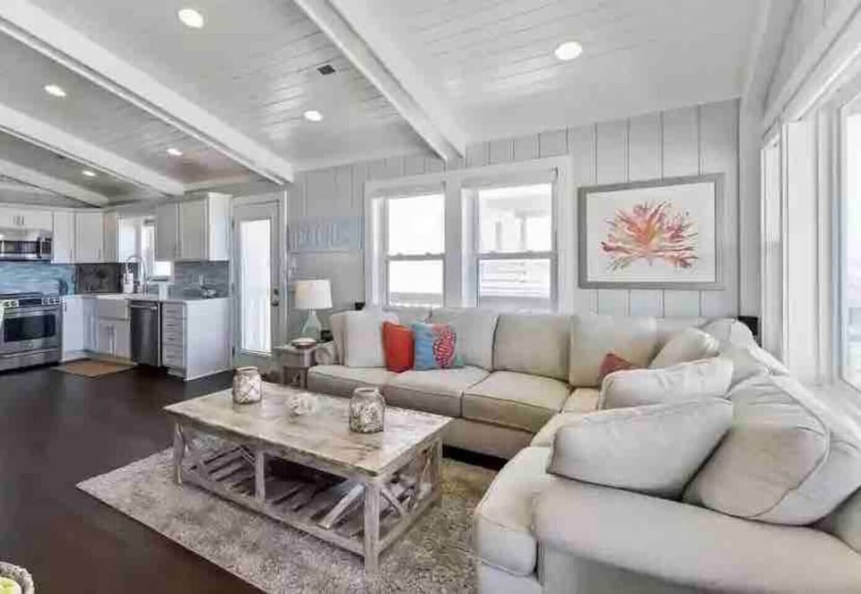 Living room with large sofa, coffee and side tables, smart TV and ocean view.