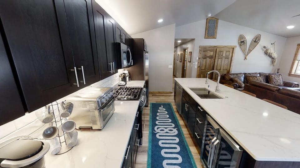 Your spacious kitchen awaits with sleek dark cabinetry, bright quartz counters, modern appliances, and an inviting open layout that flows into the cozy living area.