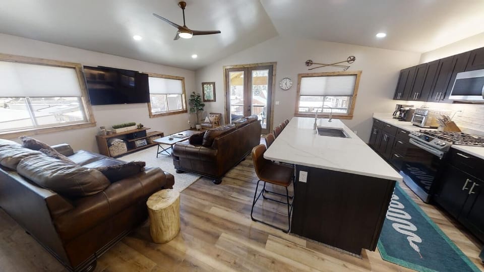 Gather with your group in this open-concept space where rustic charm meets modern comfort—leather sofas, a sleek kitchen island, and natural light create your perfect mountain retreat home base.