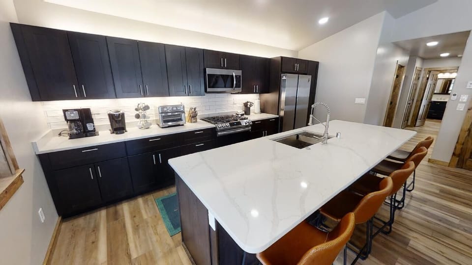 Your spacious kitchen features sleek dark cabinetry, modern stainless appliances, and a brilliant white island where you'll gather for meals and conversation.