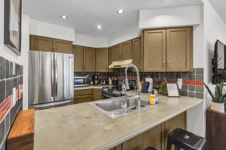 The lovely kitchen features everything you need to whip up a favorite meal from a large, single-basin sink and roomy stainless steel refrigerator and boasts a convenient bar/serving area with seats for two.