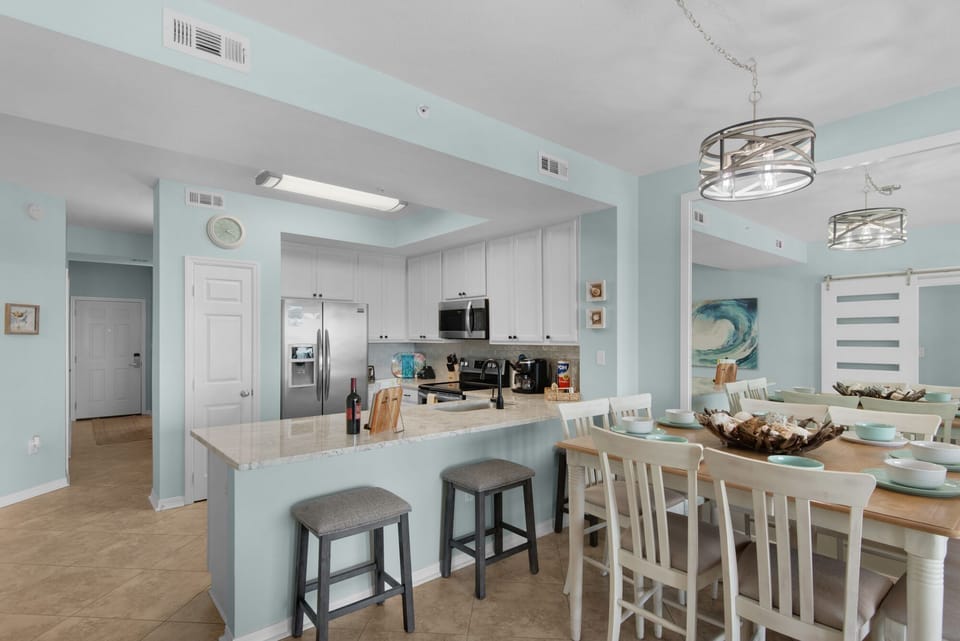 Gather around this spacious open kitchen where coastal blue walls and modern fixtures create your perfect backdrop for memorable meals together.