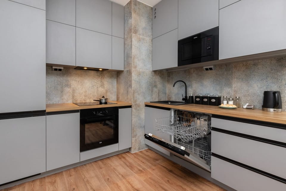  A modern kitchenette with sleek gray cabinets and wooden countertops, equipped with high-quality appliances.