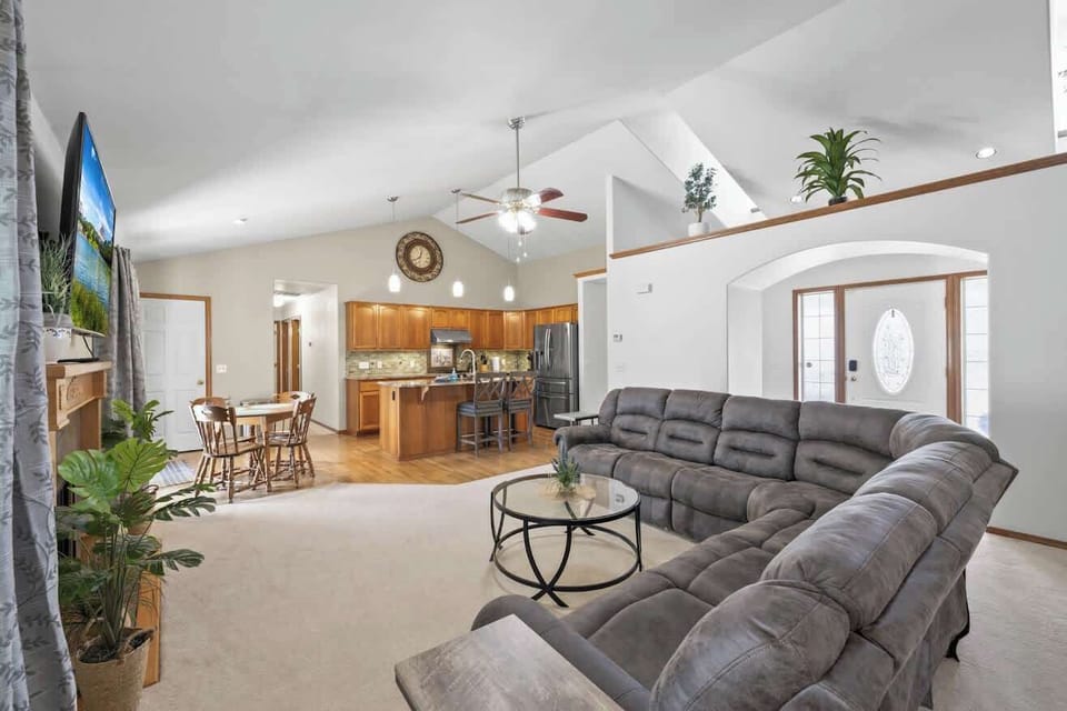 Relax in the cozy living room with a fireplace, large TV, and open-concept design connecting the kitchen and dining area.