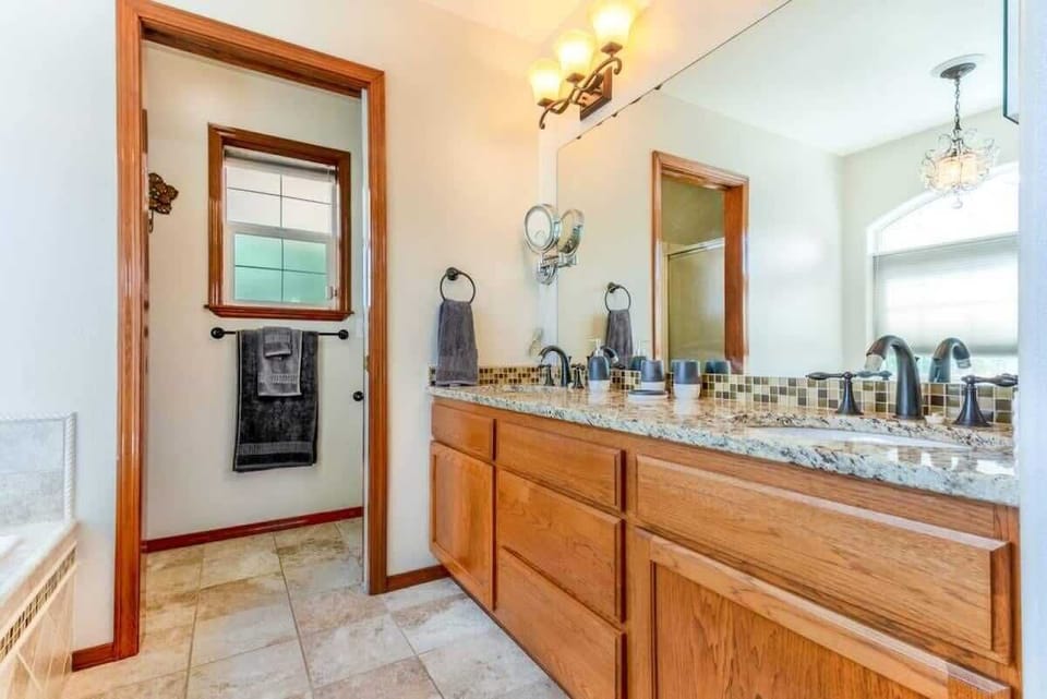 private master bathroom with double sink, toilet, tub, and standing shower