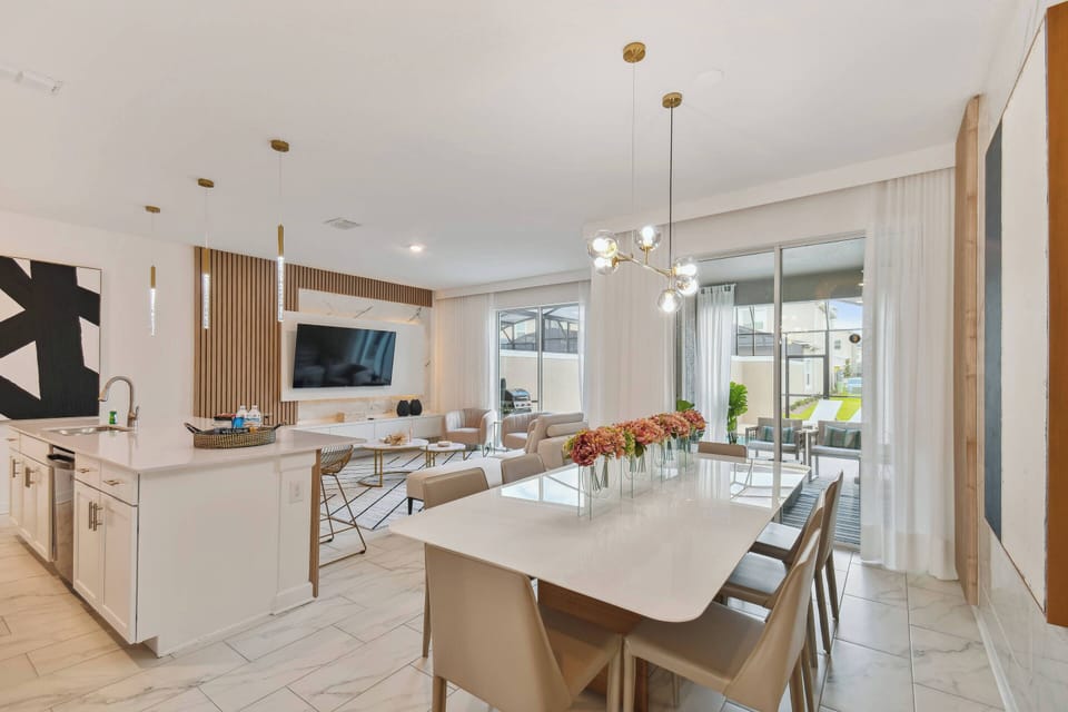 This bright, airy open-concept kitchen and dining area offers sleek cabinetry and a spacious table for family meals, along with warm decor tones and a seamless flow to the outdoor patio, perfect for relaxation.