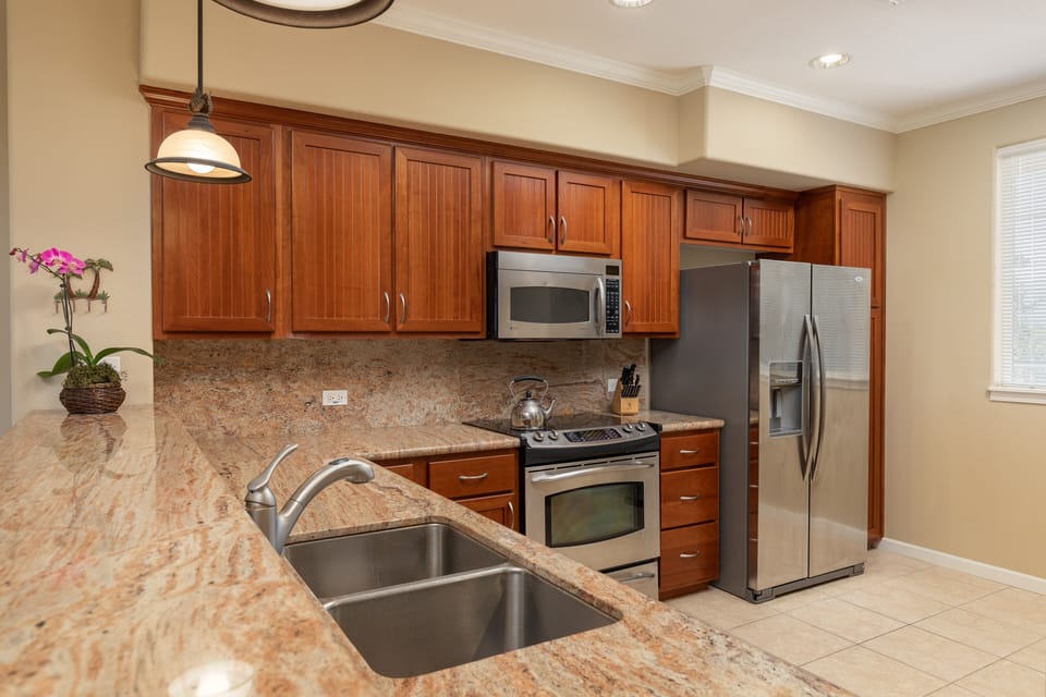 - Kitchen with rich wood cabinetry granite countertops and stainless steel appliances - Double sink breakfast bar seating and extra storage make cooking convenient - Recessed and pendant lighting keep the space bright and functional
