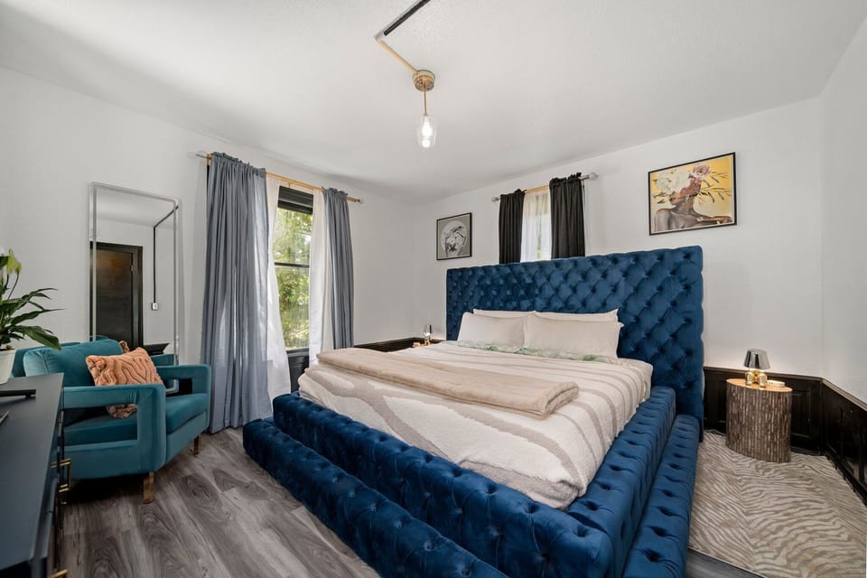 Bold blue tufted bed anchors this bright bedroom w/ cozy seating nook