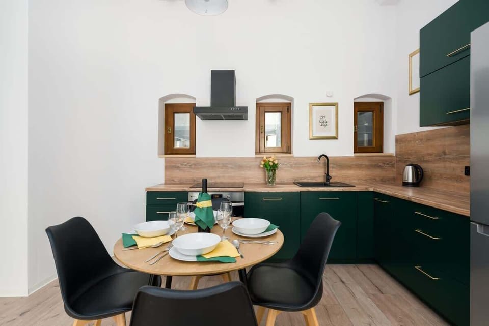 A modern kitchen with deep green cabinets, black fixtures, and a wooden countertop, combining elegance and functionality.
