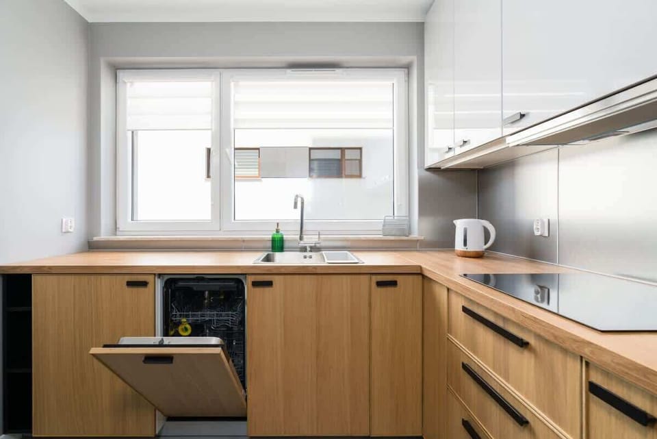 A bright kitchen with wooden cabinetry, white walls, and modern appliances, offering a clean and functional design.