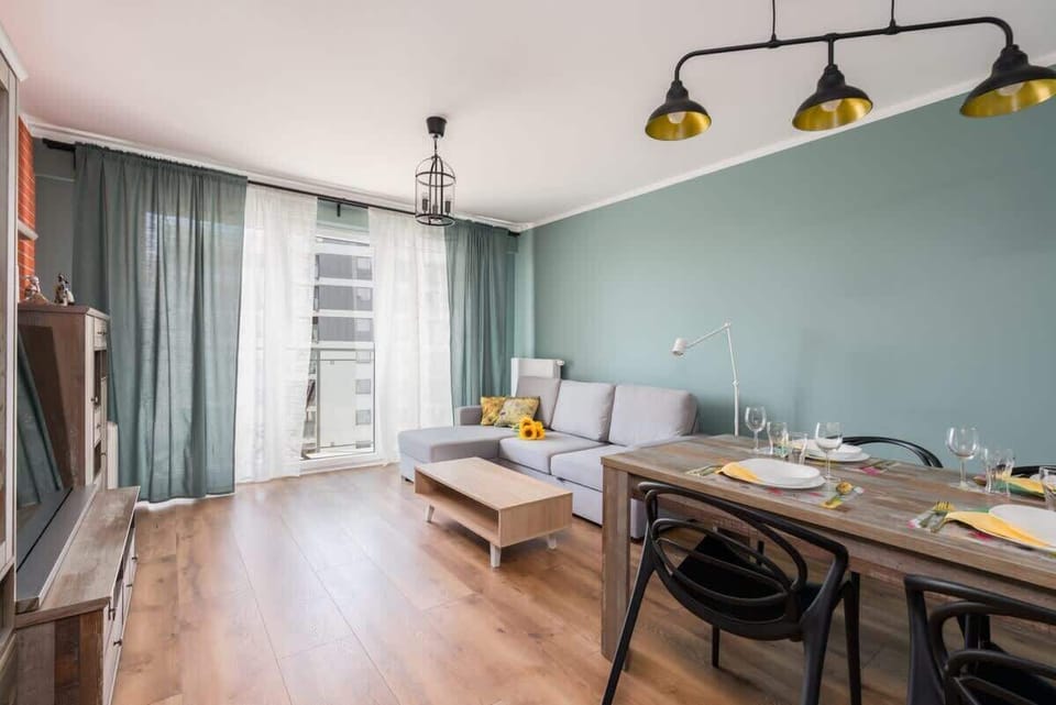 A spacious living room featuring a TV, shelving units, and a wooden floor, blending rustic and contemporary styles.